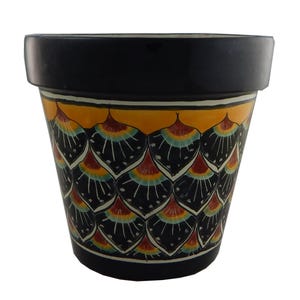 May include: A black terracotta planter with a yellow, red, and blue geometric pattern. The planter has a scalloped rim and is perfect for adding a touch of color to your home.