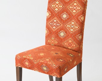 Può includere: Una sedia in legno con seduta e schienale in tessuto a fantasia rosso, arancione e giallo. La sedia ha un design semplice con quattro gambe.
