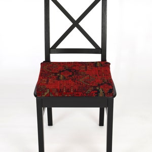 Peut inclure: Une chaise en bois noir avec un coussin &agrave; motifs rouges. La chaise a un design simple avec un dossier en forme de croix.