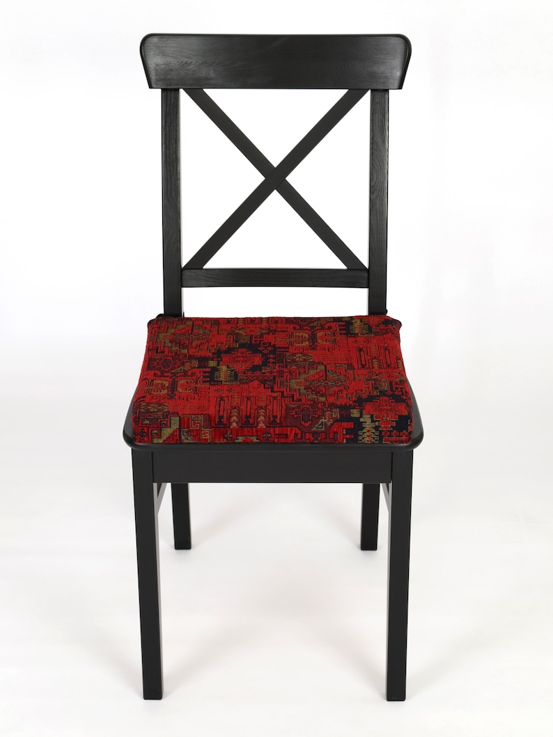 Peut inclure: Une chaise en bois noir avec un coussin &agrave; motifs rouges. La chaise a un design simple avec un dossier en forme de croix.