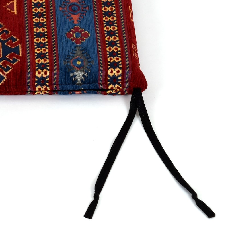May include: A red, blue, and gold patterned cushion with black drawstrings. The cushion has a traditional Turkish design.