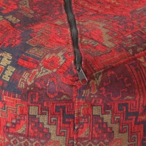 Pu&ograve; includere: Pouf in tessuto rosso e nero con chiusura a zip.