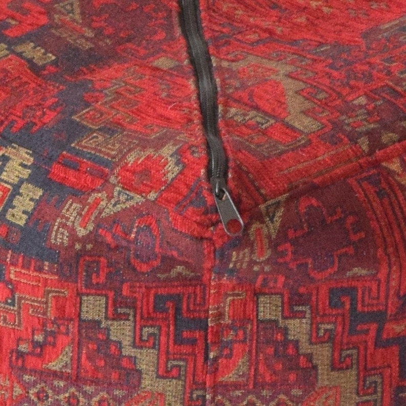 Pu&ograve; includere: Pouf in tessuto rosso e nero con chiusura a zip.