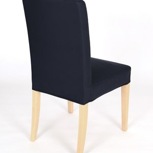 May include: A dark blue chair cover with a simple design. The cover is made of a soft, durable fabric and fits snugly over the chair. The chair has light wood legs.