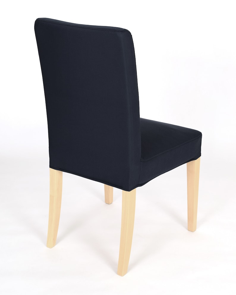 May include: A dark blue chair cover with a simple design. The cover is made of a soft, durable fabric and fits snugly over the chair. The chair has light wood legs.