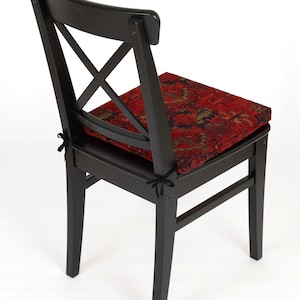 Peut inclure: Chaise en bois noir avec un coussin &agrave; motifs rouge et or. La chaise a un design simple avec un dossier en forme de croix.