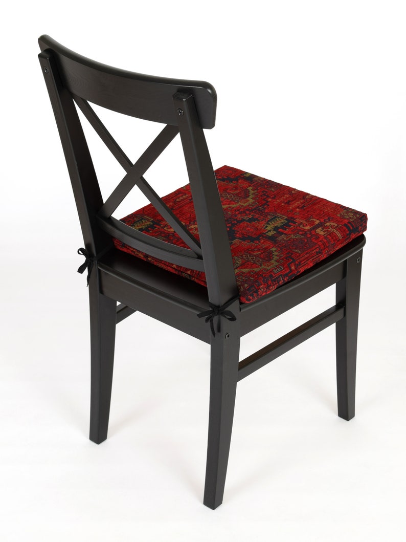 Peut inclure: Chaise en bois noir avec un coussin &agrave; motifs rouge et or. La chaise a un design simple avec un dossier en forme de croix.