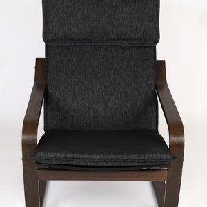 May include: A dark gray upholstered armchair with a wooden frame. The chair has a high back and curved arms. The chair is sitting on a white background.