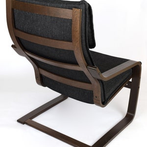 May include: A dark gray fabric armchair with a wooden frame and a curved base. The chair has a high back and a comfortable-looking seat.