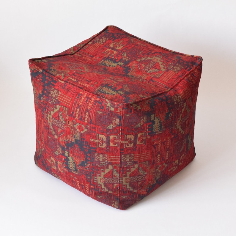 Pu&ograve; includere: Pouf quadrato rosso e oro con un design geometrico.