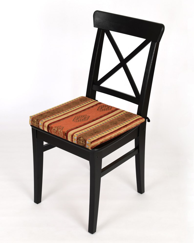 Puede incluir: Silla de madera negra con un coj&iacute;n estampado. El coj&iacute;n tiene un dise&ntilde;o geom&eacute;trico rojo, naranja y dorado.