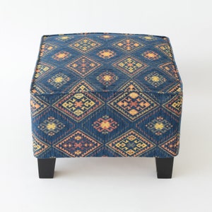 May include: A blue and orange patterned ottoman with black legs. The ottoman has a square top and a geometric design.
