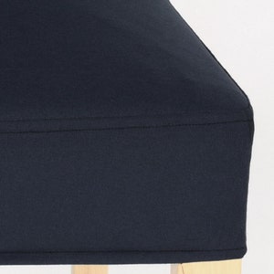 May include: A dark blue chair cushion with a simple design. The cushion is made of a soft, textured fabric and has a clean, finished edge.