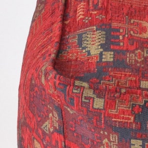 Pu&ograve; includere: Tessuto rosso con un motivo tessuto di forme geometriche in oro, nero e rosso.