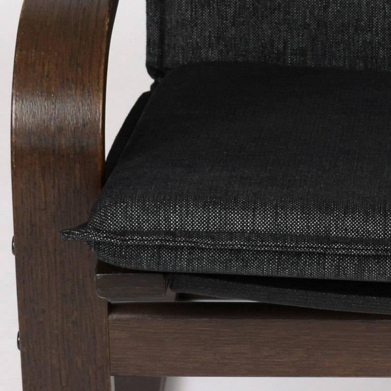 May include: A dark brown wooden chair with a black fabric cushion. The cushion has a subtle textured pattern and a stitched edge.