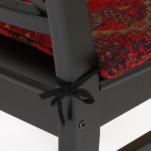 Peut inclure: Gros plan d'une chaise en bois noir avec un coussin &agrave; motifs rouges. Le coussin est fix&eacute; &agrave; la chaise avec des liens en ruban noir.