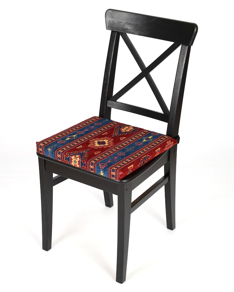May include: A black wooden chair with a red, blue, and yellow patterned cushion. The chair has a simple, classic design with a cross-shaped back.