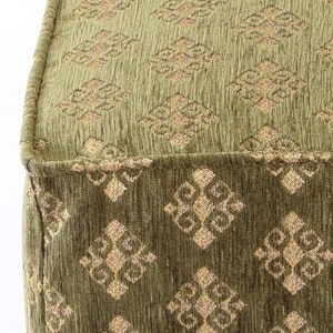 May include: A green fabric ottoman with a diamond pattern in a lighter shade of green. The ottoman has a tufted top and a square shape.
