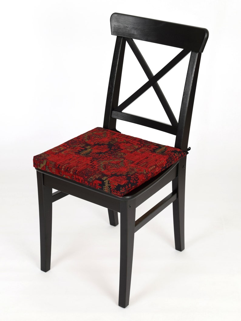 Peut inclure: Chaise en bois noir avec un coussin &agrave; motifs rouge et or. La chaise a un dossier en forme de croix.