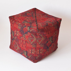 Pu&ograve; includere: Pouf quadrato rosso e oro con motivo e chiusura a zip.