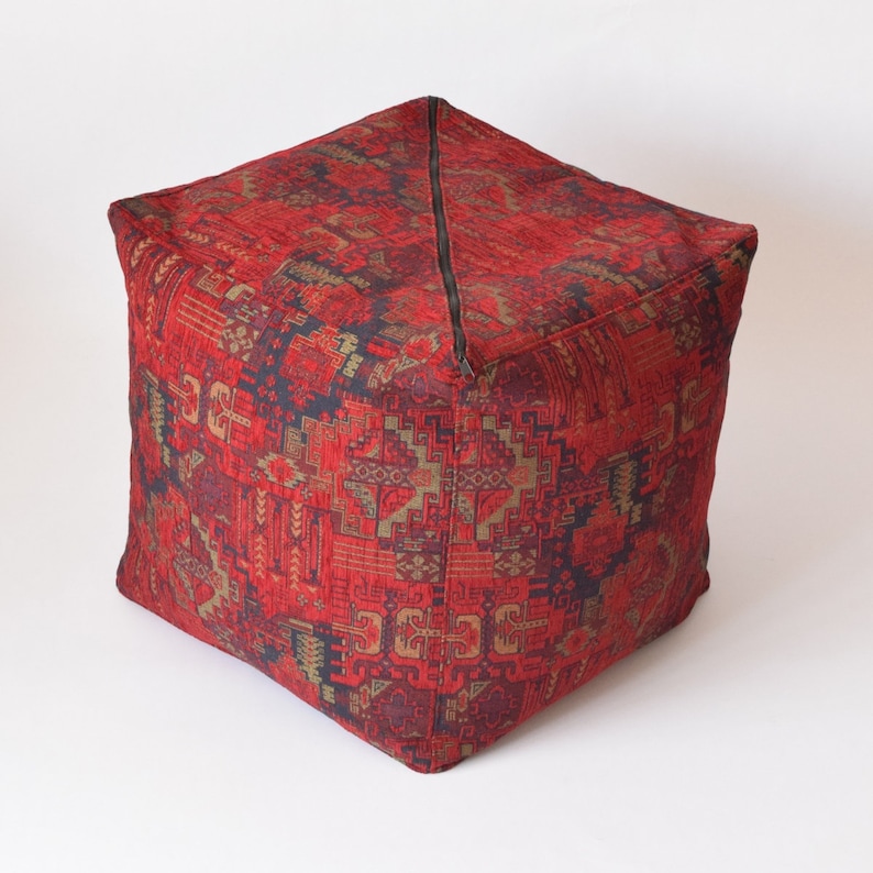 Pu&ograve; includere: Pouf quadrato rosso e oro con motivo e chiusura a zip.