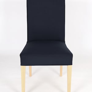 May include: A navy blue chair cover with a simple design. The cover is made of a soft, durable fabric and fits snugly over the chair. The chair has wooden legs.