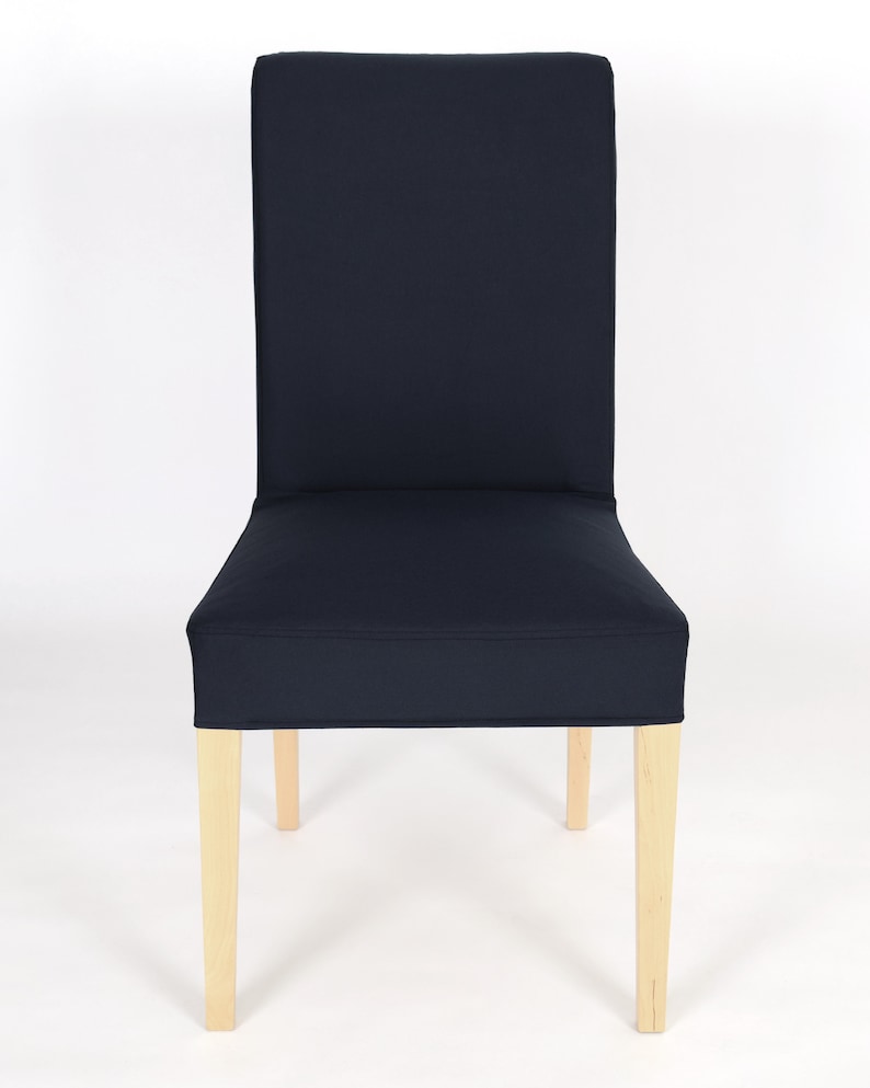 May include: A navy blue chair cover with a simple design. The cover is made of a soft, durable fabric and fits snugly over the chair. The chair has wooden legs.
