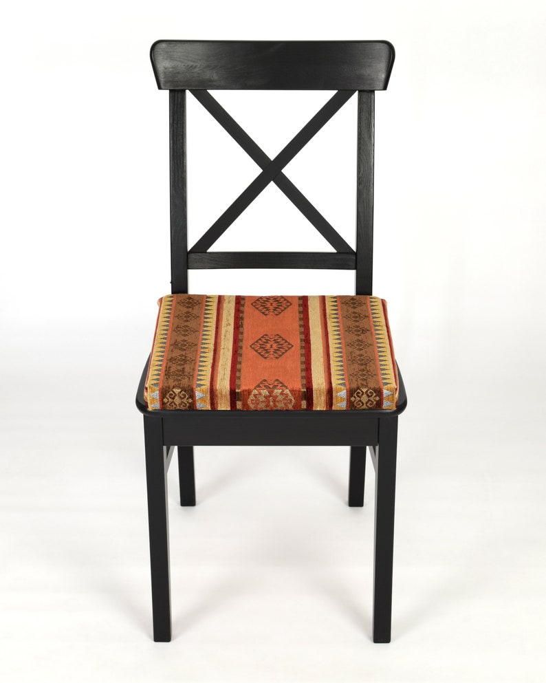 Puede incluir: Silla de madera negra con un coj&iacute;n de asiento tejido con un patr&oacute;n en tonos naranja, marr&oacute;n y beige.