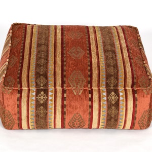 May include: A rectangular, red, brown and gold patterned floor cushion with a striped design.