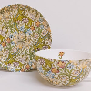 May include: A white teacup and saucer set with a floral pattern. The pattern features yellow, green, and blue flowers on a white background.