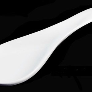 May include: A white ceramic spoon rest with a long handle. The spoon rest is designed to hold a spoon or ladle while cooking.