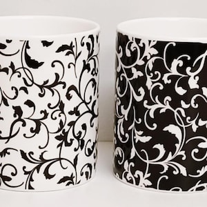 Pode incluir: Conjunto de quatro canecas de cerâmica branca com um padrão floral preto e branco. As canecas têm um design simples e são perfeitas para uso diário.