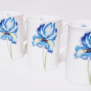 Può includere: Set di quattro tazze in ceramica bianca con disegni di fiori di iris blu ad acquerello.