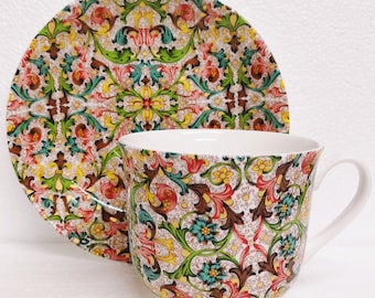 Könnte beinhalten: Ein weißes Tee-Set mit Untertasse und einem bunten Blumenmuster. Das Muster zeigt grüne, gelbe, rote und braune Blumenmotive.