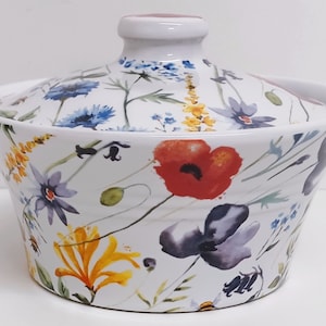 May include: White ceramic bowl with a lid, featuring a floral pattern with red, yellow, blue, and purple flowers. The bowl is decorated with a watercolour-style design.