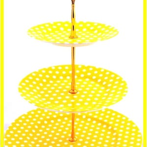 May include: A three-tiered cake stand with a gold metal base and yellow plates with white polka dots.