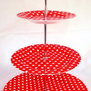May include: A three-tier cake stand with a silver metal stand and red and white polka dot plates.
