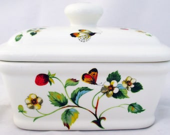 May include: White ceramic butter dish with a lid. The dish is decorated with a floral design featuring strawberries, leaves, and butterflies in shades of red, yellow, green, and blue.