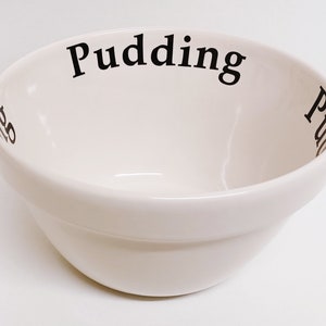 Könnte beinhalten: Weiße Keramikschüssel mit dem Wort "Pudding" in Schwarz am Rand.