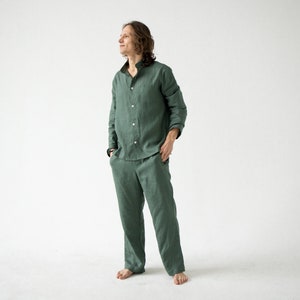 May include: A green linen pajama set. The set includes a long-sleeved button-down shirt and matching pants. The shirt has a mandarin collar and the pants have pockets. The fabric appears to be lightweight and breathable.