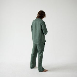 May include: A green linen pajama set, including a long-sleeved shirt and matching pants. The shirt has a button-down front and the pants have a relaxed fit. The outfit is made of a lightweight fabric.