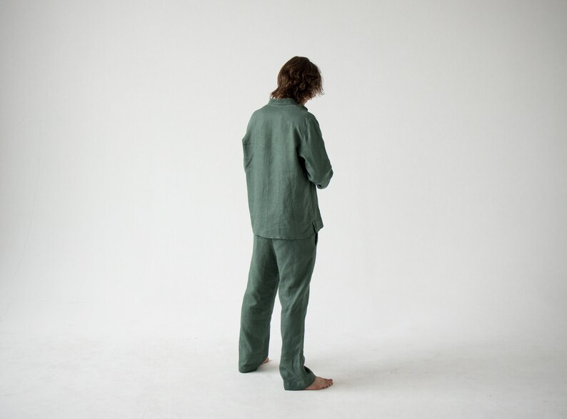 May include: A green linen pajama set, including a long-sleeved shirt and matching pants. The shirt has a button-down front and the pants have a relaxed fit. The outfit is made of a lightweight fabric.