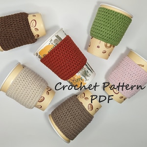 May include: Six crocheted coffee cup cozies in various colors, including brown, red, green, beige, pink, and gray. The cozies are on top of disposable coffee cups with a coffee bean pattern. The text "Crochet Pattern PDF" is written in black on a white background.