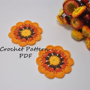 May include: Two crocheted orange, brown and yellow coasters with a flower design. Crochet Pattern PDF.