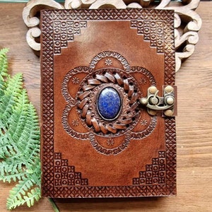 May include: A brown leather journal with an intricate embossed design and a blue gemstone clasp.