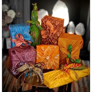May include: A collection of gifts wrapped in colorful fabric, featuring various patterns and textures. The gifts are arranged on a wooden table with a gold tray.