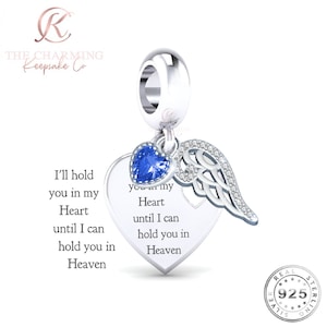 May include: A silver charm with a heart-shaped pendant, a blue gemstone heart, and a wing design. The pendant has the inscription "I'll hold you in my Heart until I can hold you in Heaven."