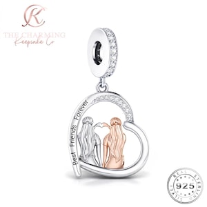 May include: A heart-shaped charm pendant featuring two figures with long hair, one in silver and one in rose gold, forming a heart shape with their hands. The silver frame is engraved with the text Best Friends Forever and accented with small clear stones.