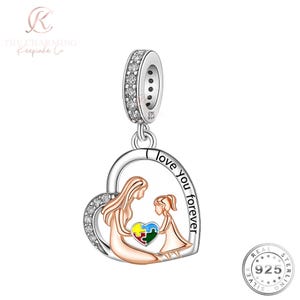 May include: A silver charm with a heart-shaped pendant. The pendant depicts a mother and child holding a puzzle piece, with the words "love you forever". The charm has a crystal-studded bail. The charm is made of 925 sterling silver.