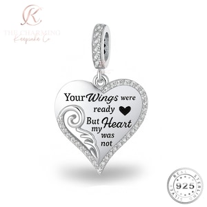 May include: A silver heart-shaped charm pendant with the inscription "Your Wings were ready But my Heart was not." The charm is adorned with clear crystals and a small wing design. The pendant is attached to a silver bail with more crystals.